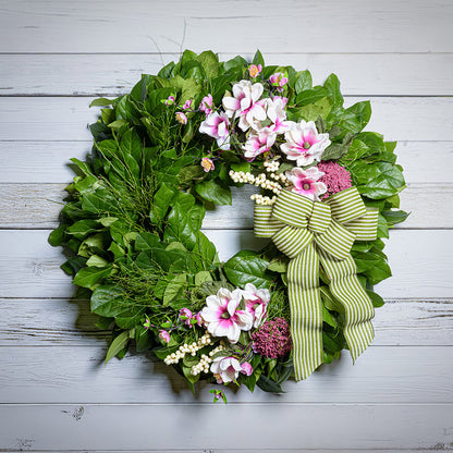 Floral wreath with green bow on a wooden background