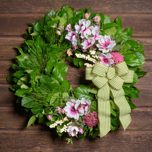 Floral wreath with greenery and a striped bow on a wooden background