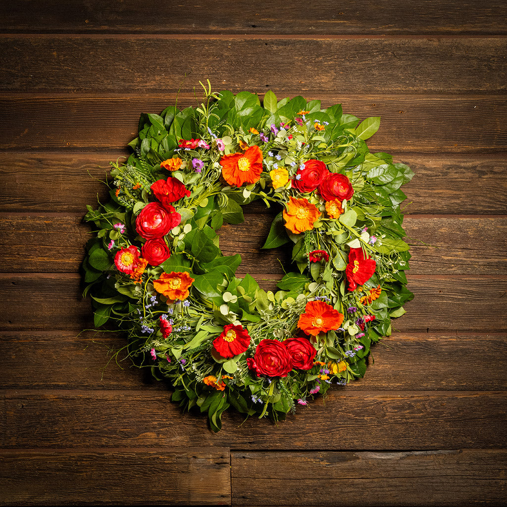 Fresh salal and sweet huckleberry with mixed colors of faux poppy flowers and faux red ranunculus flowers