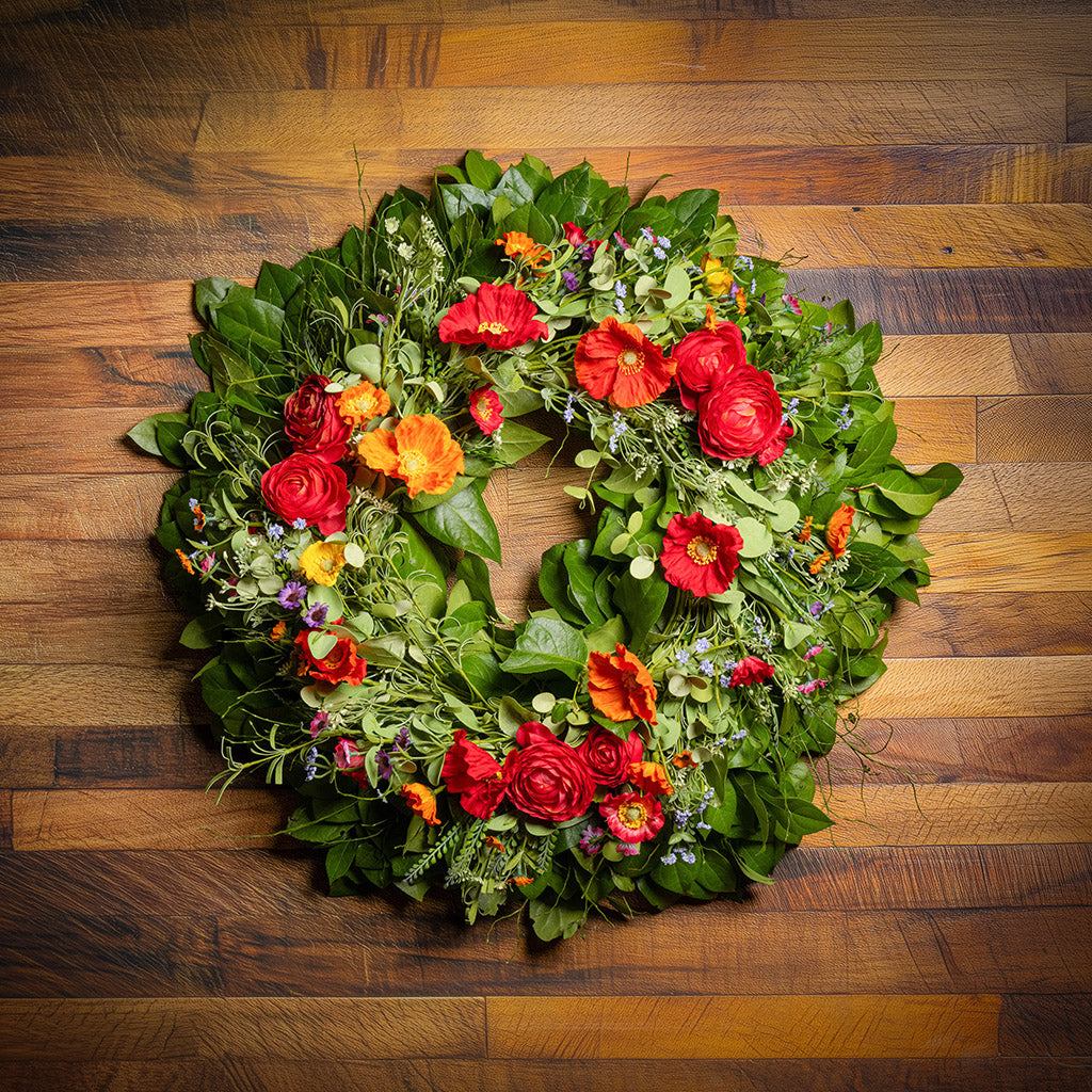 Fresh salal and sweet huckleberry with mixed colors of faux poppy flowers and faux red ranunculus flowers