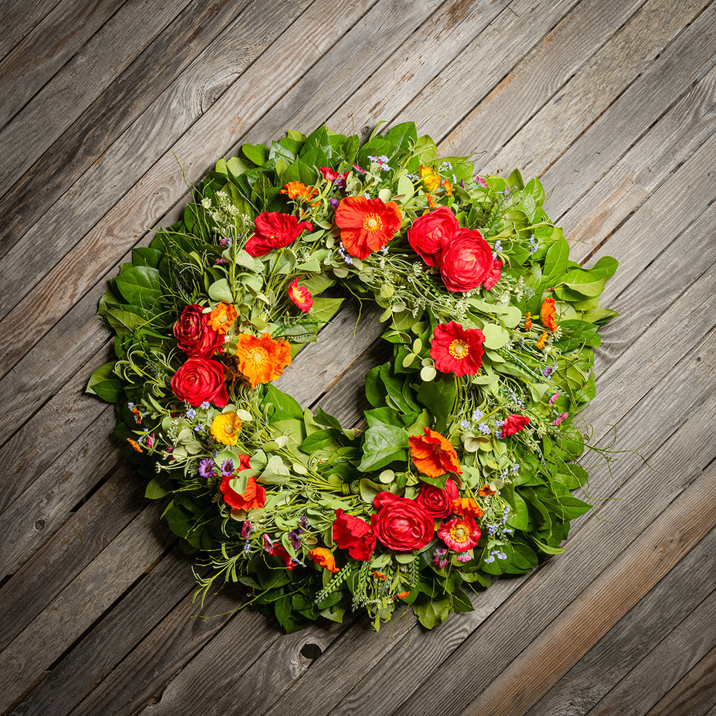 Fresh salal and sweet huckleberry with mixed colors of faux poppy flowers and faux red ranunculus flowers