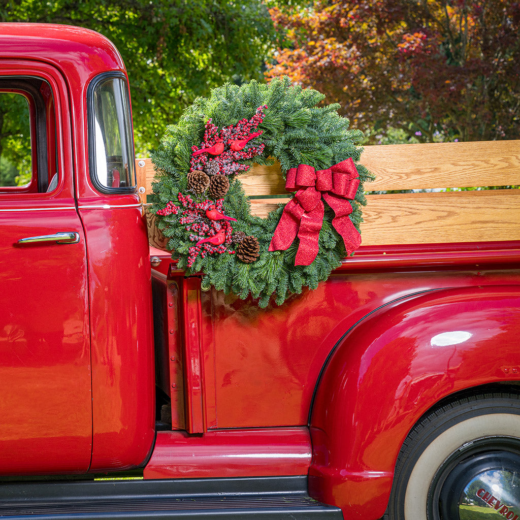 red cardinals with red berries and red sparkle bow on evergreen wreath