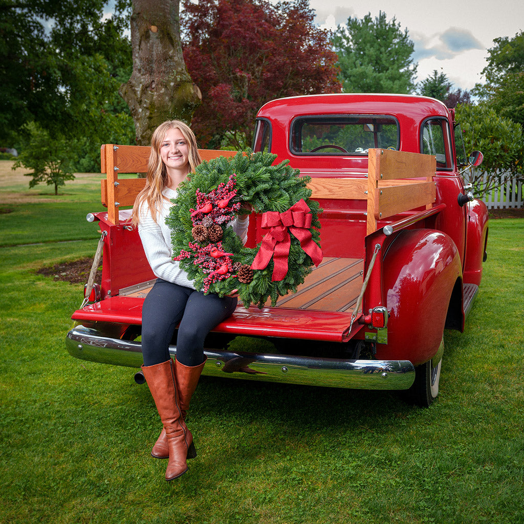 red cardinals with red berries and red sparkle bow on evergreen wreath