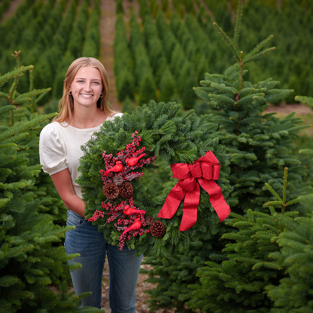 red cardinals with red berries and red sparkle bow on evergreen wreath