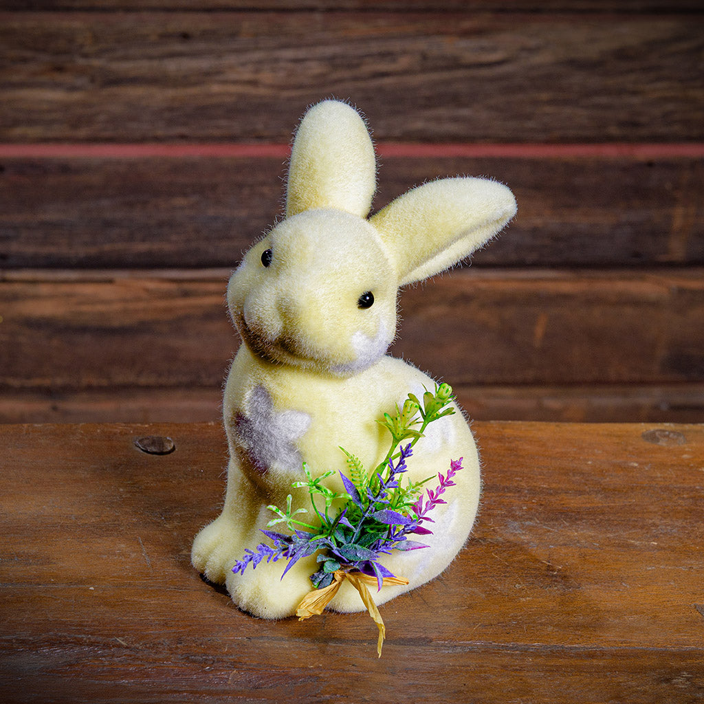 Soft rabbit toy with a bundle of flowers on a wooden surface