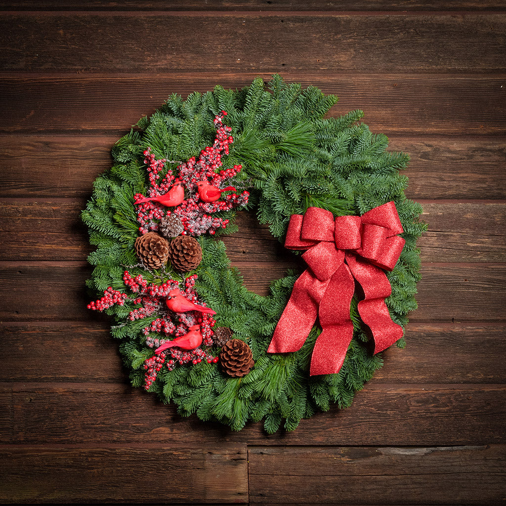 red cardinals with red berries and red sparkle bow on evergreen wreath