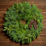 Christmas wreath with bay leaves, pine cones with no bow close up on a dark wood background.