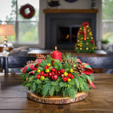 Centerpiece made of noble fir, cedar, and pine with ponderosa pine cones, Australian pine cones, red ball clusters, red and green faux berry picks, red-and-green plaid bow tucks, and a red pillar candle displayed on a wooden table