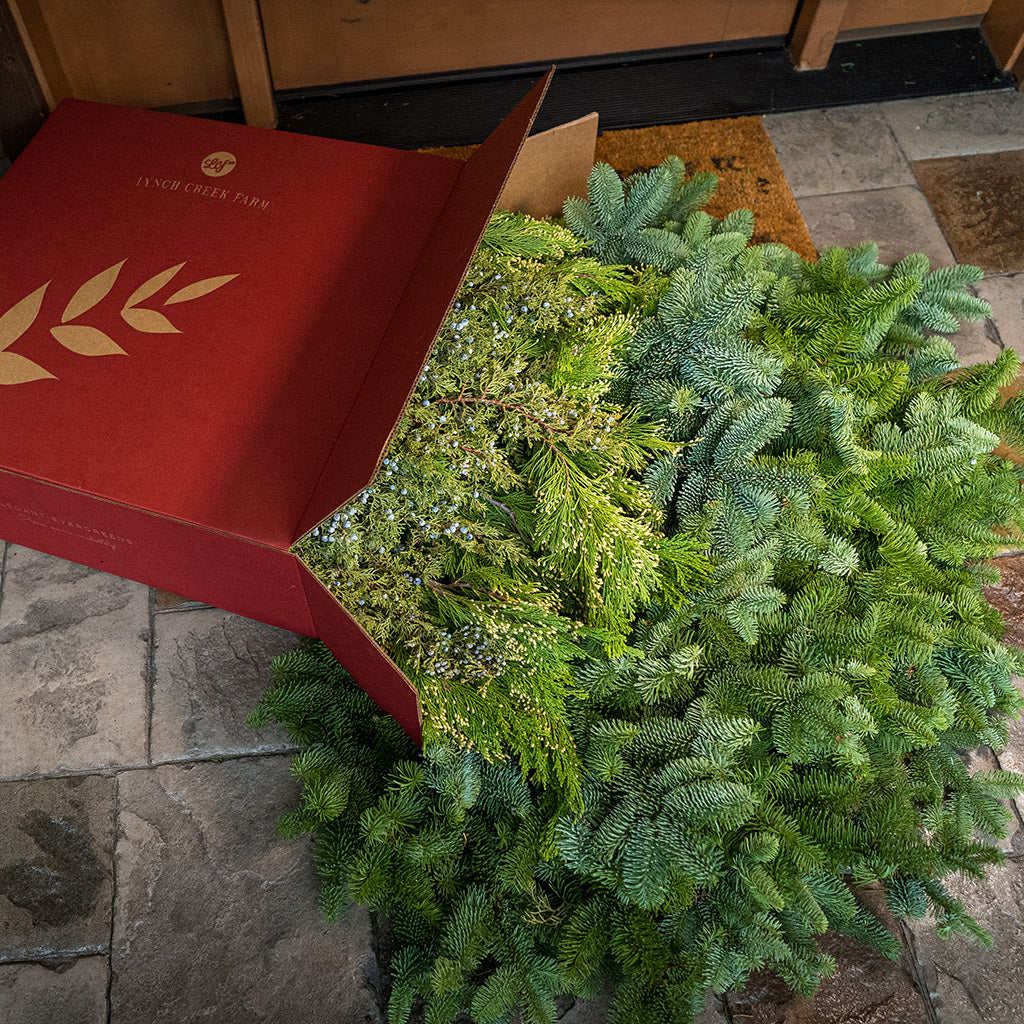 Loosely boxed 14 lbs of Noble Fir in 6"-24” length pieces, 3 lbs of Incense Cedar in 6" - 18" length pieces, and 3 lbs of Juniper in 6" - 12" length pieces laying on a front porch.