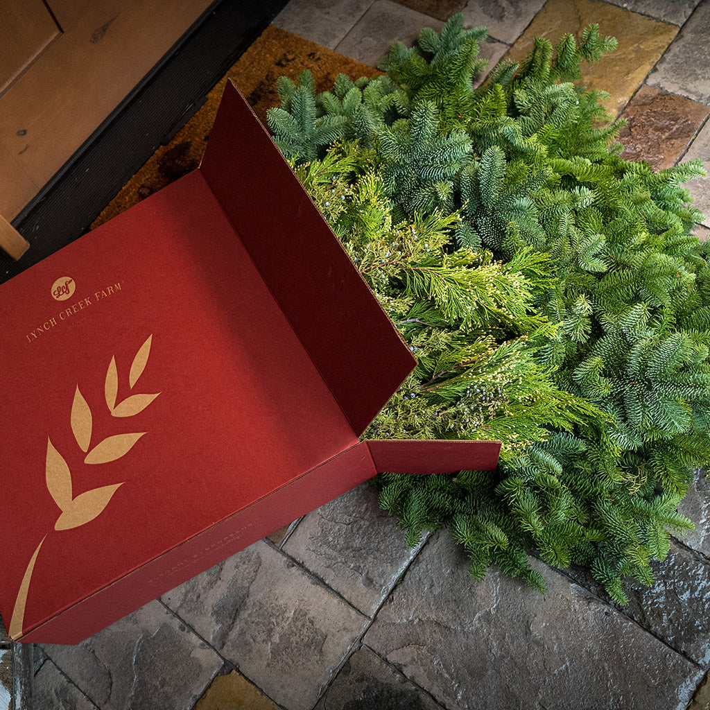 Loosely boxed 14 lbs of Noble Fir in 6"-24” length pieces, 3 lbs of Incense Cedar in 6" - 18" length pieces, and 3 lbs of Juniper in 6" - 12" length pieces laying on a front porch.