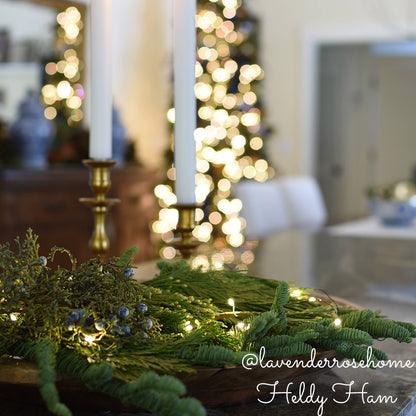 Close up loosely arranged Noble Fir in 6"-24” length pieces, Incense Cedar in 6" - 18" length pieces, and Juniper in 6" - 12" length pieces laying at the base of candles.