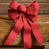 Brushed Linen Red bow shown sitting on a wood bench with a dark wood background.