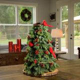 Tabletop tree of noble fir with a rustic berry garland, 3 cardinal birds, and a nest on a wooden table