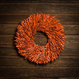 22” natural wreath is handmade with orange myrtle on a dark wood background. 