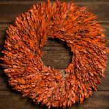 22” natural wreath is handmade with orange myrtle on a dark wood background.