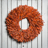22” natural wreath is handmade with orange myrtle on a white wood fence background. 