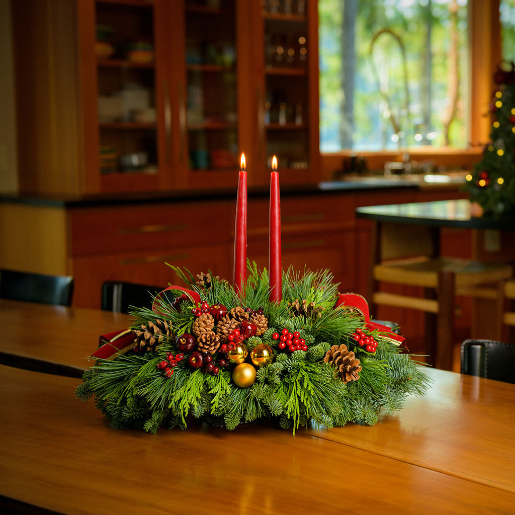 Traditional centerpiece with red balls, pine cones and berries with 2 red velveteen bows and two red taper candles 
