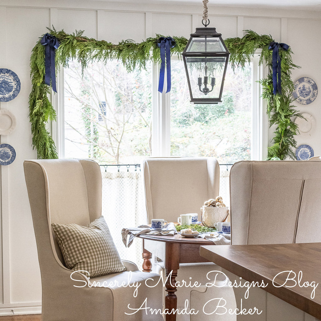 Western red cedar garland accented with blue bows hung around a dining room window..