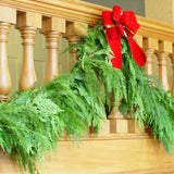 Western red cedar garland hanging from banister with red velvet bow