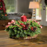 Centerpiece made of noble fir, white pine, incense cedar, red ball clusters, cinnamon-scented Australian pinecones, red and white plaid bows, real cinnamon sticks, red berry clusters, and a red pillar candle on a wooden table