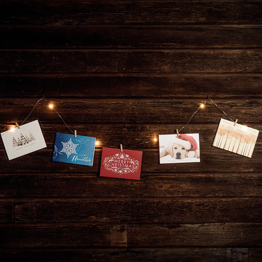 10-foot strand of white lights and holiday greeting cards hanging from mini wood clothespins with a dark wooden background.