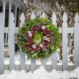 Christmas wreath made of noble fir, cedar, white pine, and bay leaves with 9 frosted Australian pine cones, and a ring of frosted branches with faux burgundy berries hanging on a white fence