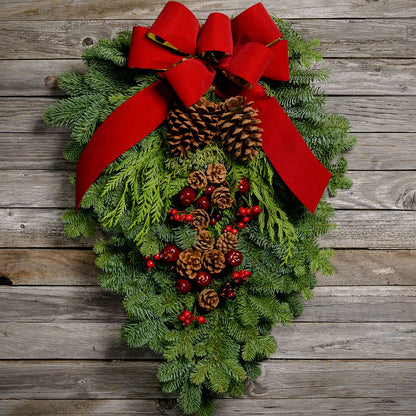 Christmas Swag made with fir cedar juniper pine cone glittery branches silver balls and red bow on wooden background