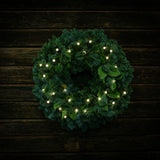 White, globe shaped, cracked glass effect battery operated lights on a evergreen wreath shown illuminated