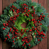 Christmas wreath with metallic red berries, pine cones, bay leaves on fir, pine and cedar base