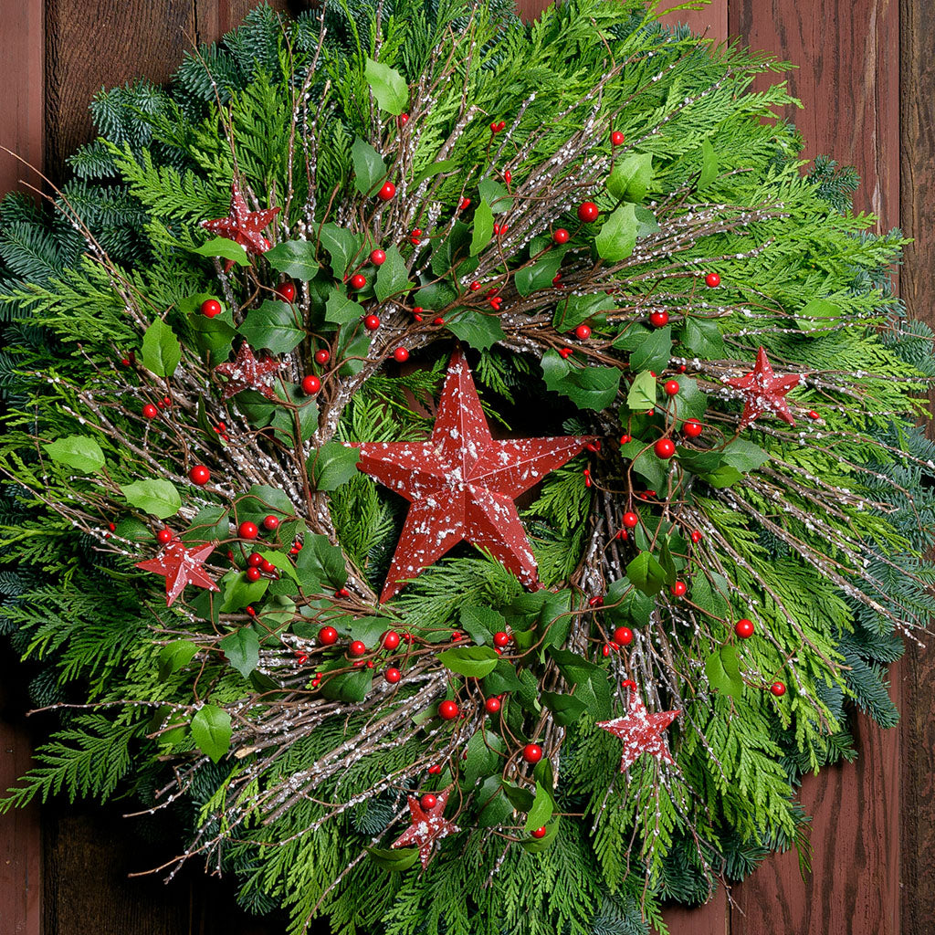 Farmhouse holiday Christmas wreath with speckled red, rustic stars, berries, holly and twigs on a base of noble and cedar