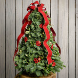 Fresh hand-assembled tabletop Christmas tree with fir, variegated holly, red berries and a red velveteen bow and white LEDs