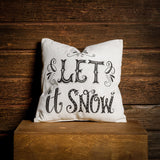 Let it Snow accent pillow in cream with black lettering on a wooden background. 
