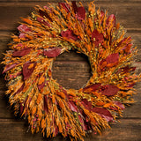 Burgundy salal leaves, dijon oats, orange phalaris, natural flax, and red flax are perfectly blended in to a 22" wreath on a dark wood background. 