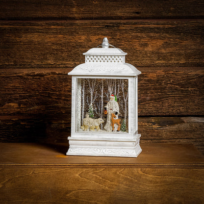 A Lighted Water Globe in white of Father Christmas with forest animals and snow-covered trees with a dark wood background.