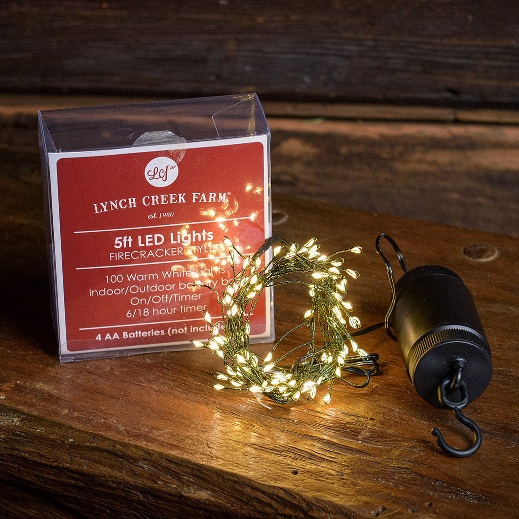 White, uniquely-shaped, battery operated lights with their packaging with a dark wood background.