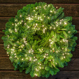 White, uniquely-shaped, battery operated lights on a evergreen wreath with a dark wood background.