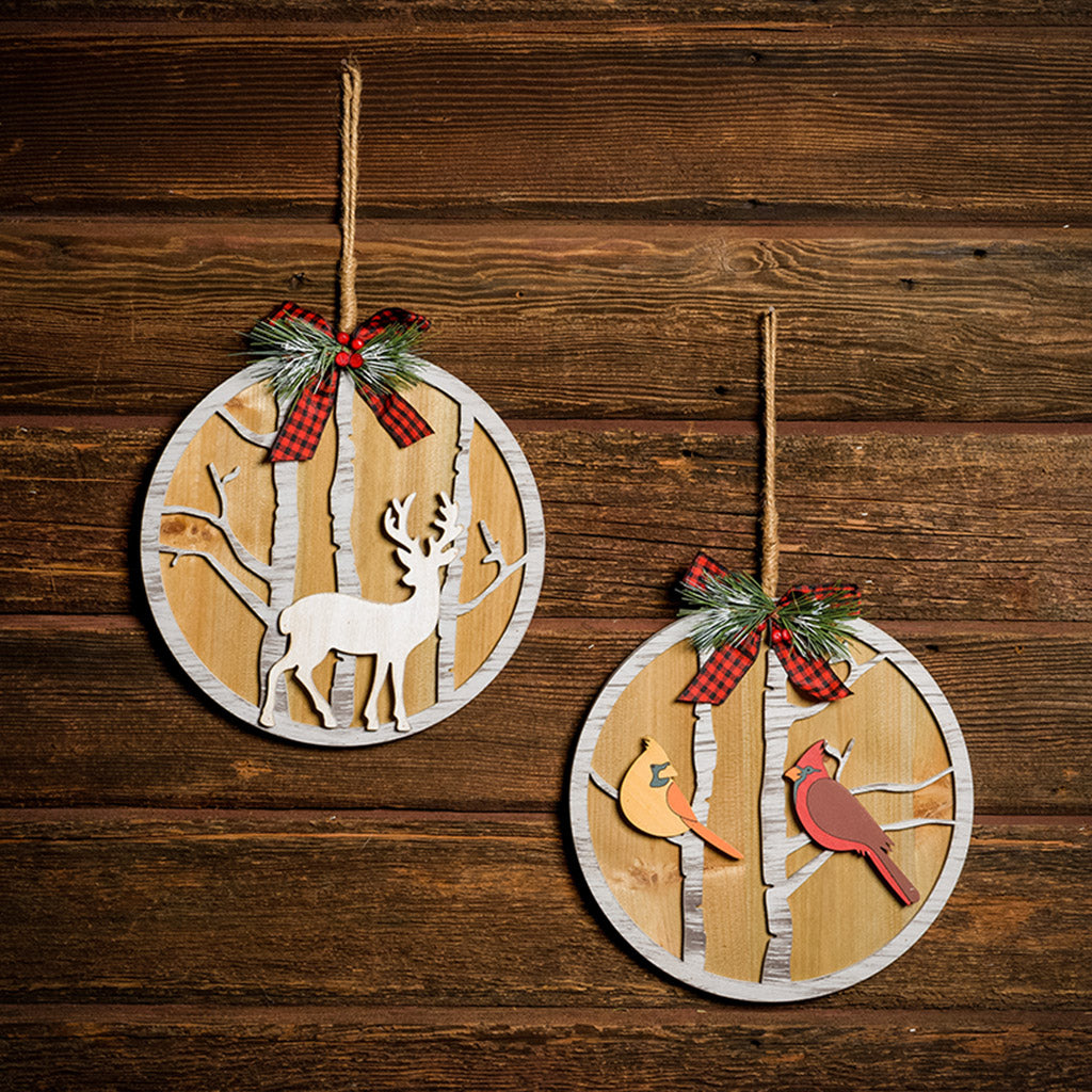 Set of 2 10 inch circular signs with deer and birds hanging on a dark wooden background.