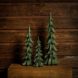 Set of 3 green resin evergreen trees with a dark wooden background.