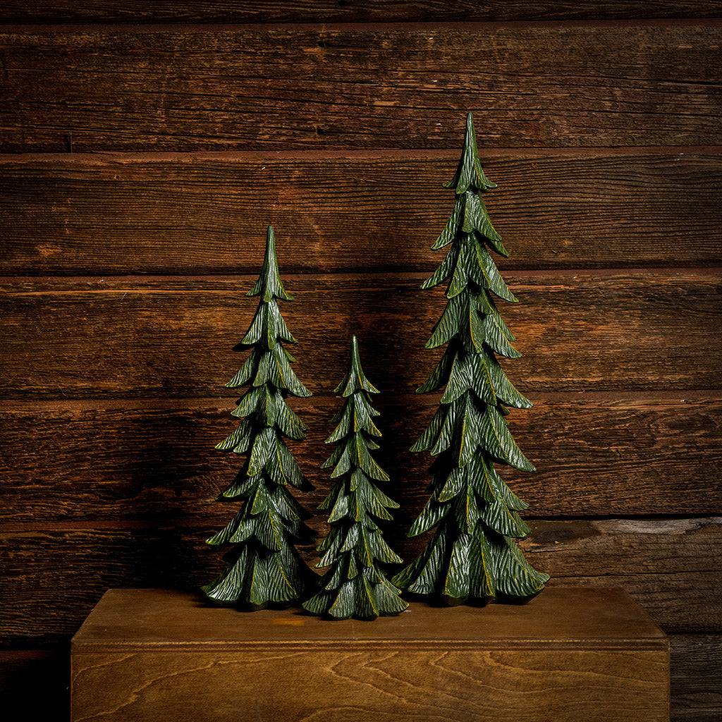 Set of 3 green resin evergreen trees with a dark wooden background.