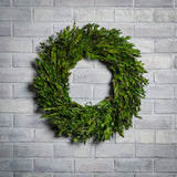 22” wreath is lovingly handcrafted with all natural preserved green myrtle on a white brick background.