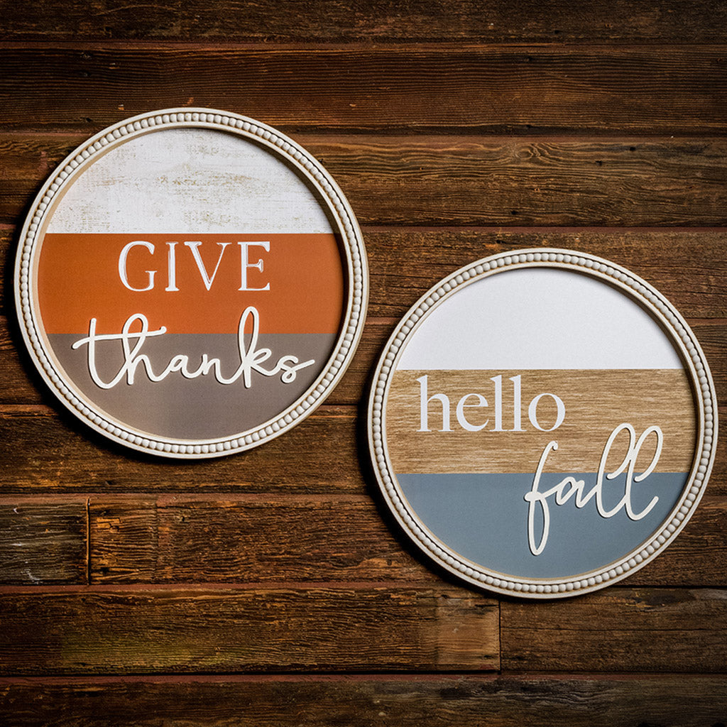 Set of 2 19" round wooden signs saying give thanks and hello fall hung on dark wooden background.