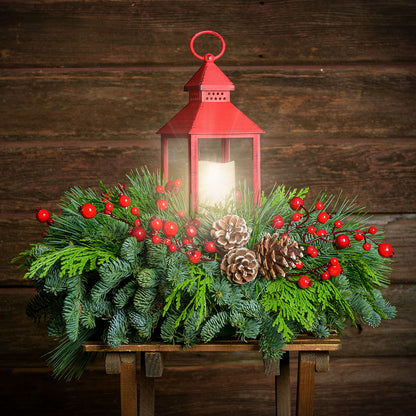 Centerpiece of noble fir, cedar, red berry branches, frosted pine cones, red LED lantern