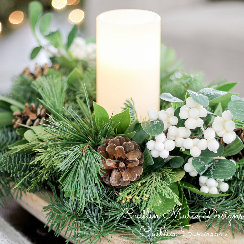 Centerpiece made of noble fir, pine, cedar and bay leaf with white berry clusters, Australian pine cones and 1 white LED pillar candle close up