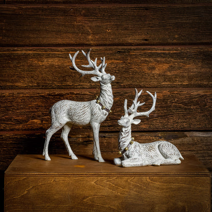 Set of 2 off-white reindeer with jingle bell collars with a dark wood background.