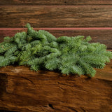 20 pounds of loose Noble Fir with a dark wood background.