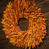 22” wreath made with a blend of yellow and orange myrtle on a dark wood background. 