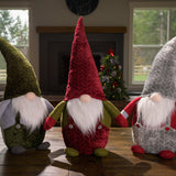 32” Gnomes weighted at the bottom with their noses poking out of tall pointy hats, their fuzzy white beards, and outfits sitting on a wood table