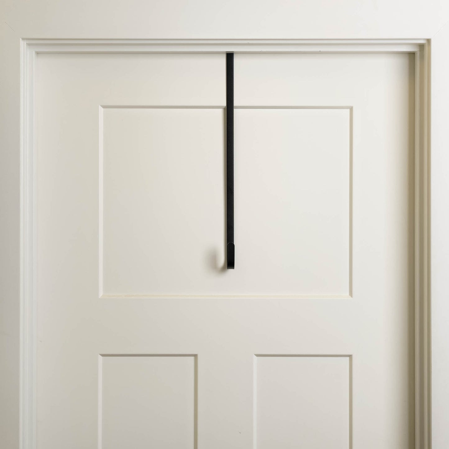 Antiqued bronze metal over the door wreath hanger on white door