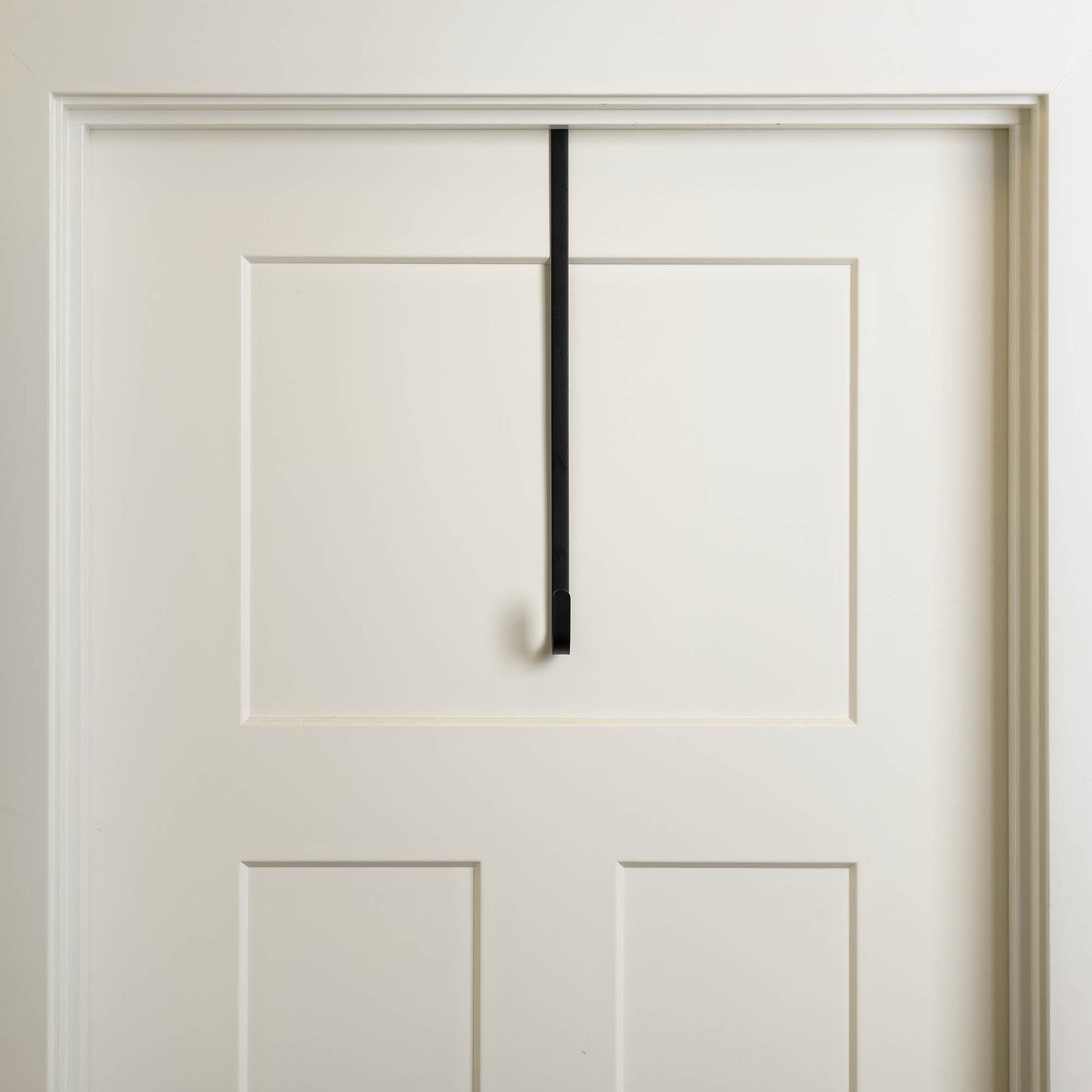 Antiqued bronze metal over the door wreath hanger on white door