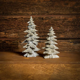 Set of 2 silver glitter trees with a dark wood background.